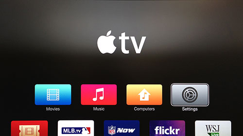 Ekran Apple TV z podświetlonym przyciskiem Ustawienia.